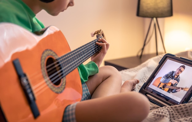 Foto gratuita la niña aprende a tocar la lección de video musical en línea de la guitarra