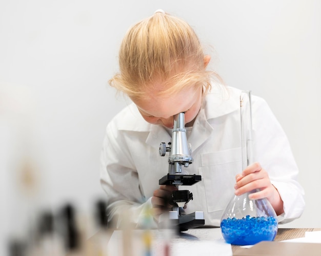 Niña aprendiendo a hacer ciencia con microscopio