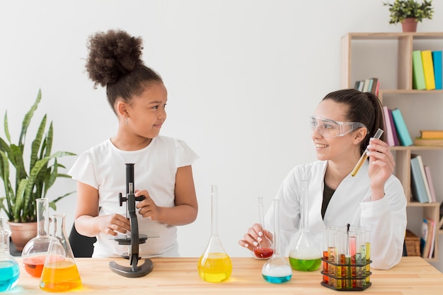 Niña aprendiendo química de una mujer científica