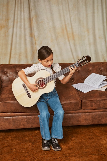 Niña aprendiendo a tocar la guitarra en casa