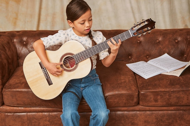 Niña aprendiendo a tocar la guitarra en casa