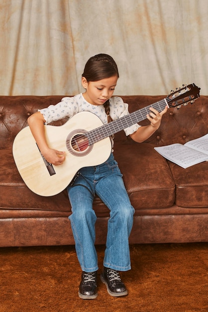 Niña aprendiendo a tocar la guitarra en casa