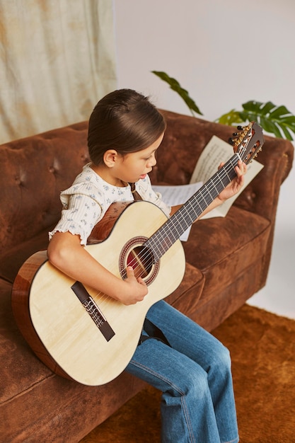 Niña aprendiendo a tocar la guitarra en casa