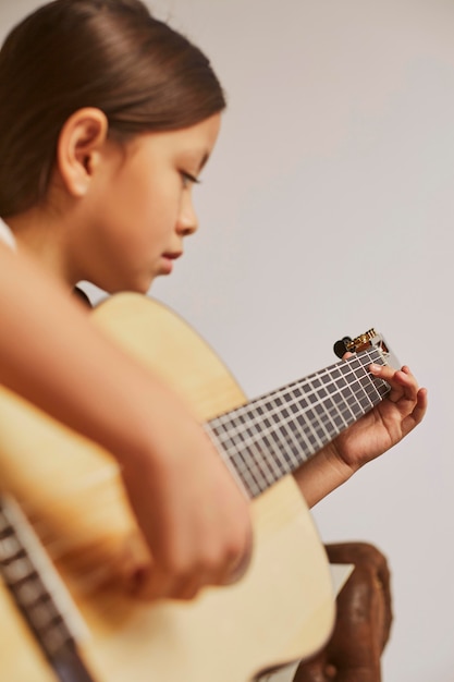 Niña aprendiendo a tocar la guitarra en casa