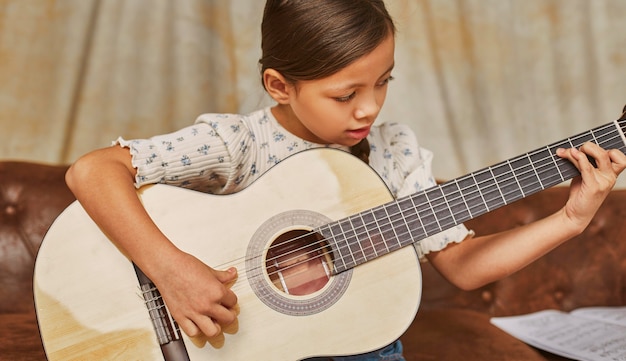 Niña aprendiendo a tocar la guitarra en casa