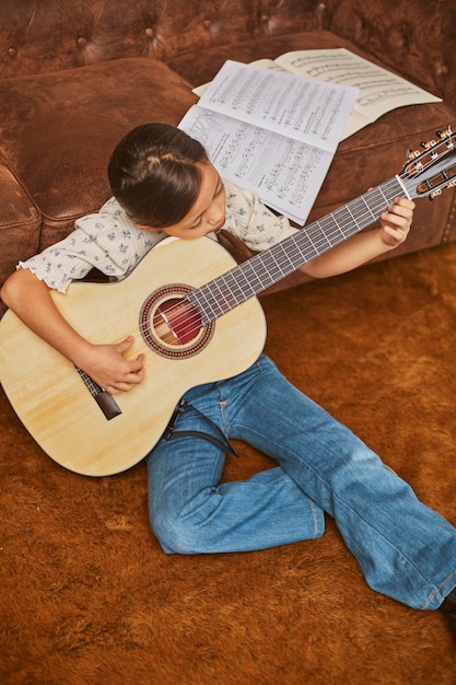 Niña aprendiendo a tocar la guitarra en casa