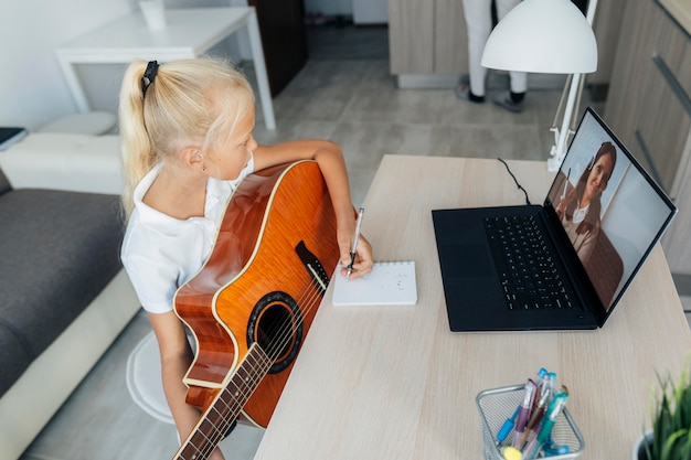 Foto gratuita niña aprendiendo a tocar la guitarra