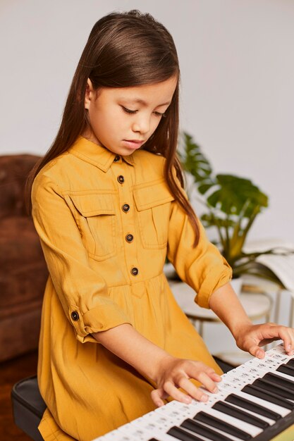 Niña aprendiendo a tocar el teclado electrónico en casa