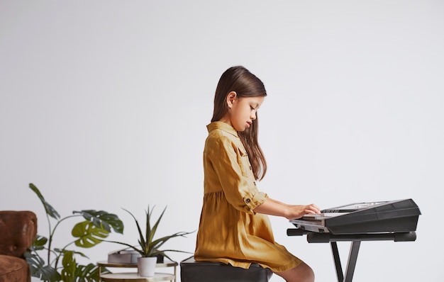 Foto gratuita niña aprendiendo a tocar el teclado electrónico