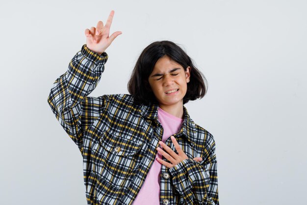 Niña apuntando hacia arriba en camisa, vista frontal de la chaqueta.