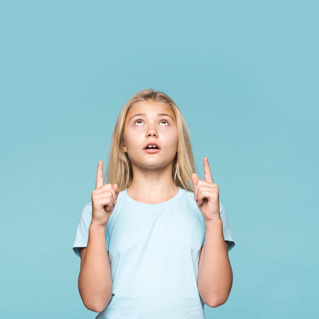 Niña apuntando hacia arriba con espacio de copia