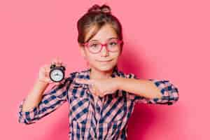 Foto gratuita niña apuntando a reloj