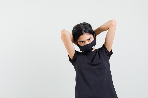 Niña arreglando su cabello en camiseta negra, vista frontal de la máscara.