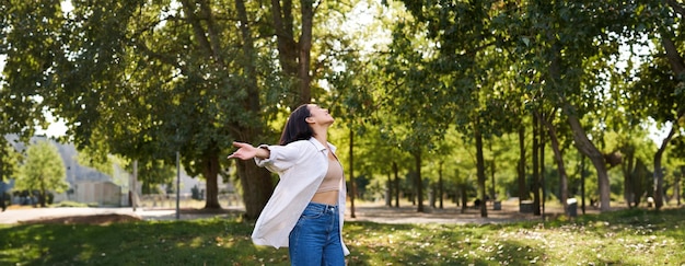 Foto gratuita niña asiática despreocupada bailando sintiendo felicidad y alegría disfrutando del sol en un día de verano caminando en el parque