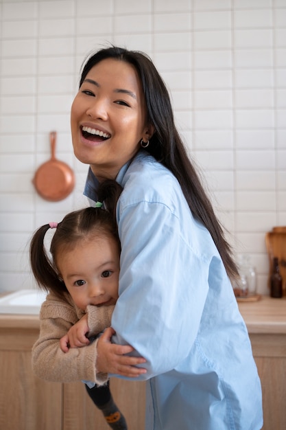 Niña asiática gastando en casa en la cocina con su madre