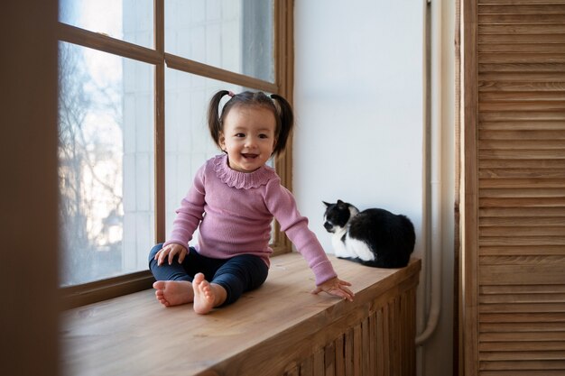 Niña asiática que pasa tiempo en casa con su gato mascota