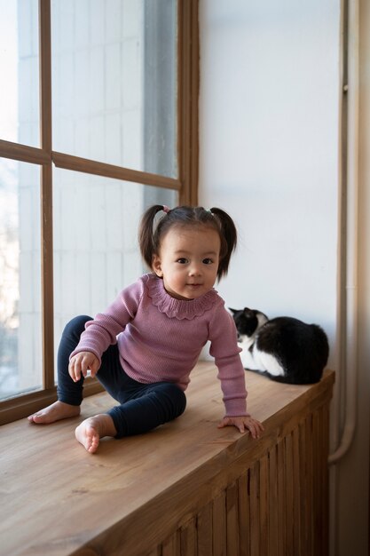 Niña asiática que pasa tiempo en casa con su gato mascota