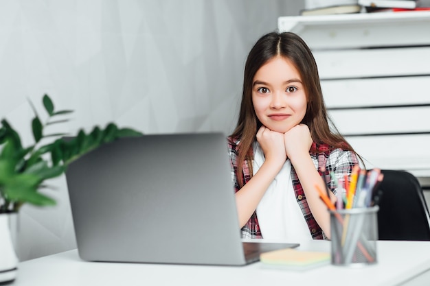 Niña atractiva que usa la computadora portátil en casa en su tiempo libre