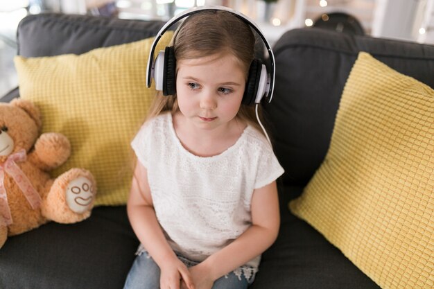 Niña con auriculares en casa