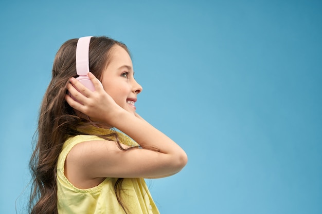 Foto gratuita niña con auriculares, escuchando música y sonriendo