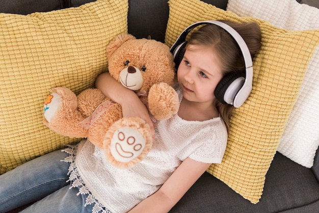 Niña con auriculares y peluche