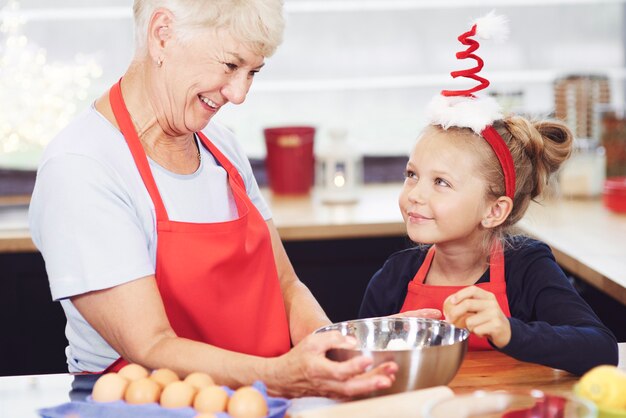 Niña ayudando a la abuela a hacer galletas para Navidad