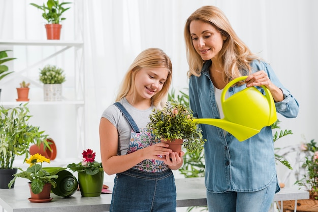 Niña ayudando a mamá a regar flores