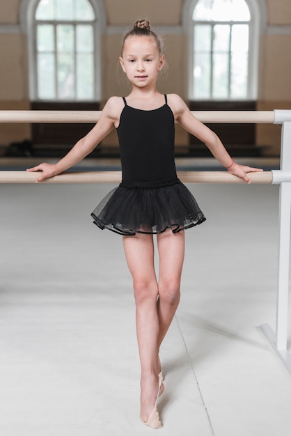 Foto gratuita niña bailarina de pie frente a la barra