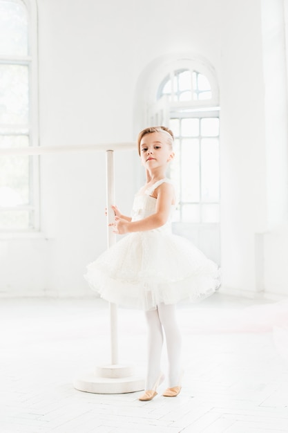 Niña bailarina en un tutú. Adorable niño bailando ballet clásico en un estudio blanco.