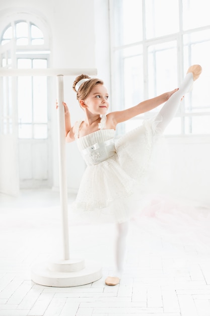 Niña bailarina en un tutú. Adorable niño bailando ballet clásico en un estudio blanco.