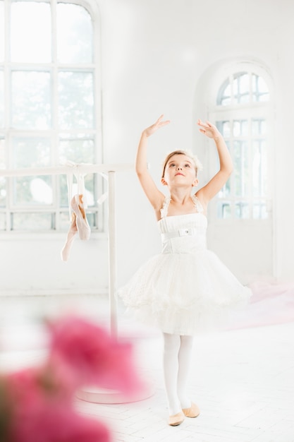 Niña bailarina en un tutú. Adorable niño bailando ballet clásico en un estudio blanco.