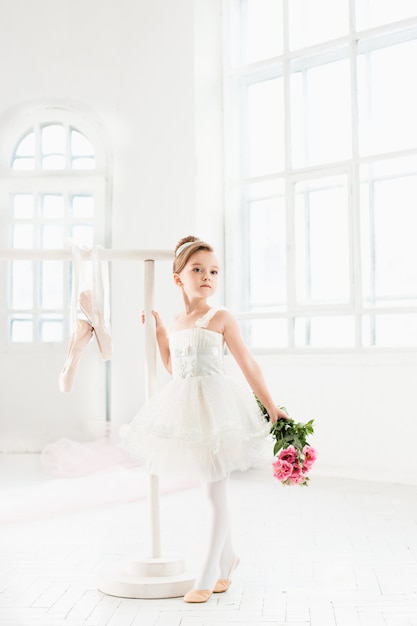 Niña bailarina en un tutú. Adorable niño bailando ballet clásico en un estudio blanco.