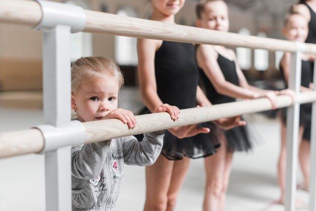 Niña con bailarines de pie cerca de la barra de madera