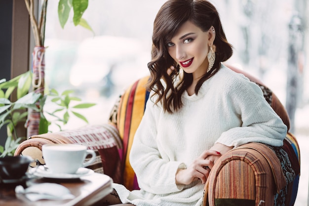 Niña bebiendo café en una cafetería de moda