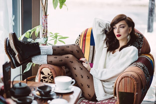 Niña bebiendo café en una cafetería de moda