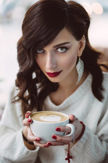 Niña bebiendo café en una cafetería de moda