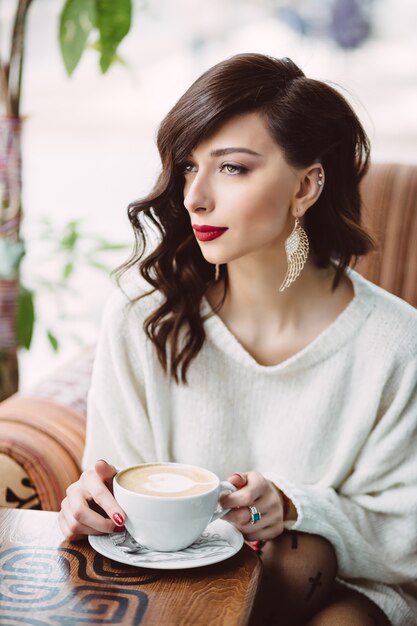 Niña bebiendo café en una cafetería de moda