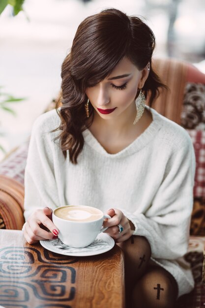 Niña bebiendo café en una cafetería de moda