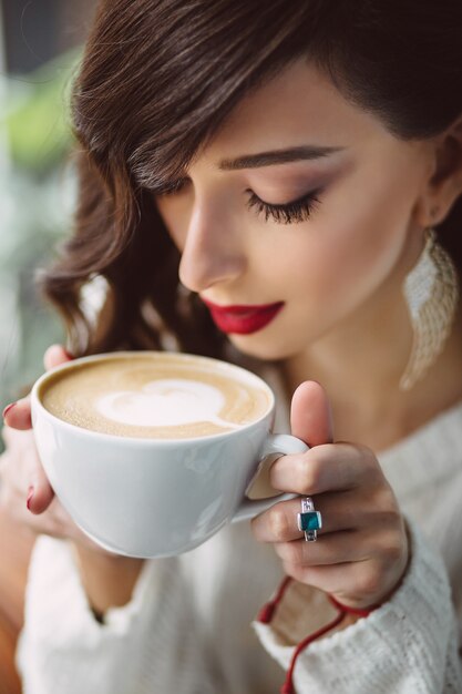 Niña bebiendo café en una cafetería de moda