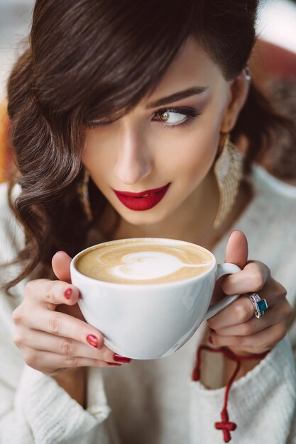 Niña bebiendo café en una cafetería de moda