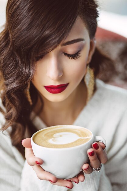 Niña bebiendo café en una cafetería de moda