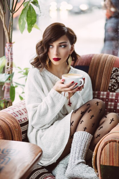 Niña bebiendo café en una cafetería de moda