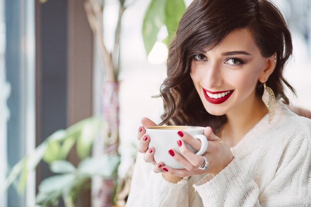 Niña bebiendo café en una cafetería de moda