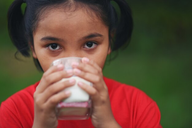 Niña bebiendo leche en el parque