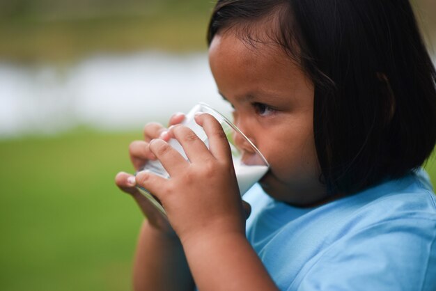 Niña bebiendo leche en el parque