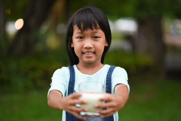 Niña bebiendo leche en el parque