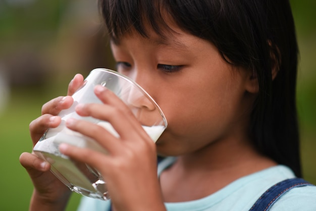 Niña bebiendo leche en el parque