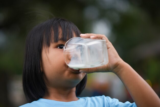 Niña bebiendo leche en el parque