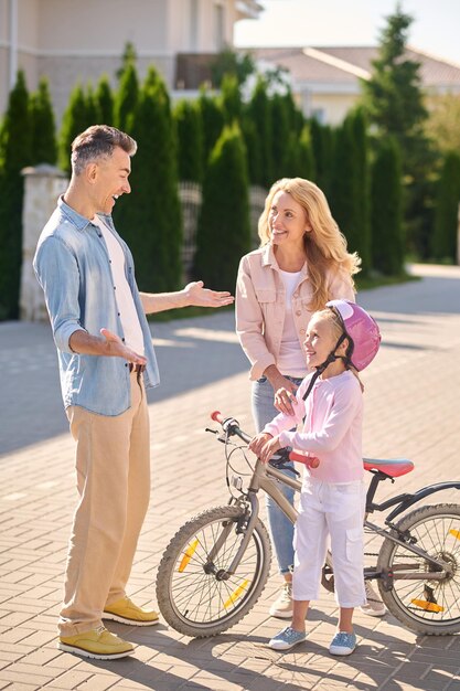 Una niña en bicicleta mientras sus padres la miran.