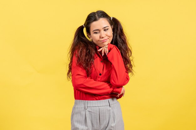 niña en blusa roja con expresión aburrida en amarillo